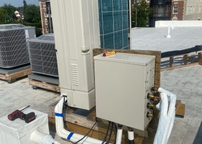Electrical box and HVAC units on a flat rooftop with tools and insulated pipes visible.