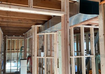 Wood framing and exposed ductwork in a house under construction, with unfinished walls and ceilings.