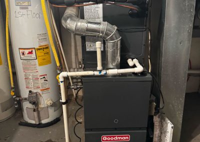 Goodman furnace and water heater installed in a basement with connected pipes and ductwork visible.