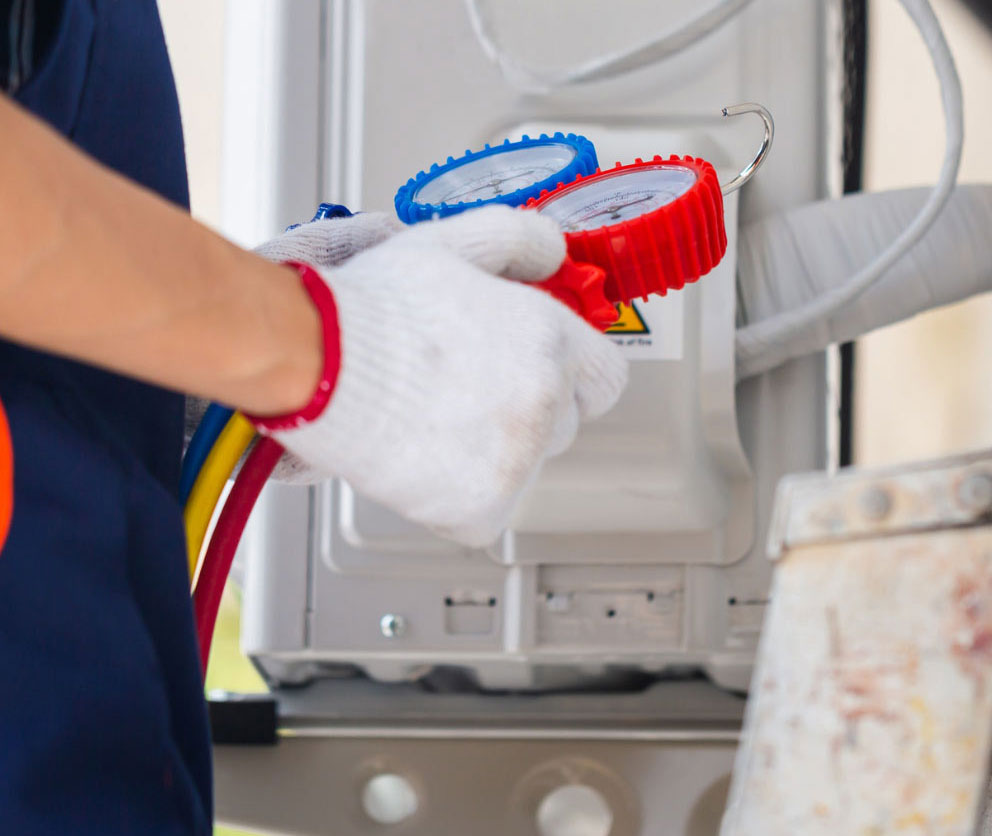 A technician checks an air conditioner using a pressure gauge manifold.