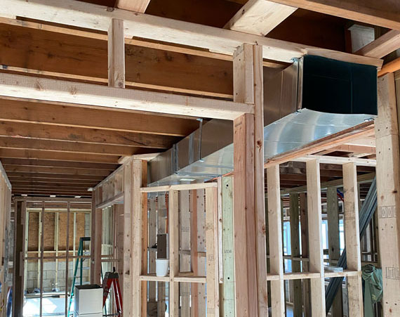 Exposed ductwork and wooden framing inside a house under construction.